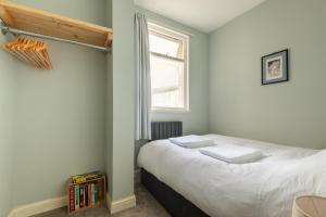 een slaapkamer met een bed met een raam en een boekenplank bij 99 Steps to the Sea in Brighton & Hove