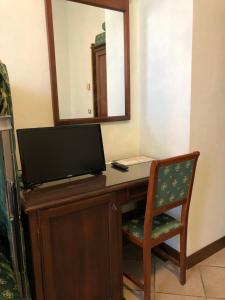 Cette chambre comprend un bureau avec une télévision et une chaise. dans l'établissement Hotel Zodiaco, à Bolsena