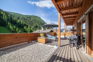 a deck with chairs and an umbrella on a house at Pritscheshof Ferienwohnung Terrasse in Malles Venosta