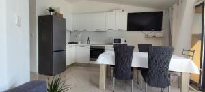 uma cozinha com uma mesa com cadeiras e um frigorífico em Apartman Mila em Marina