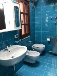 Baño azul con lavabo y aseo en B&B Villa Anna Wunderbar, en Isquia