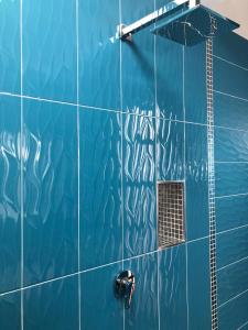 pared de azulejos azules y baño con ducha. en B&B Villa Anna Wunderbar, en Isquia
