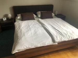 Cama con sábanas blancas y almohadas marrones en Klagenfurt`s Loft en Klagenfurt