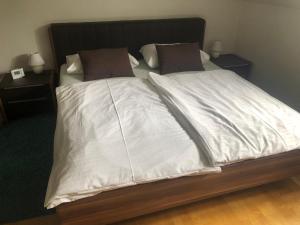 un letto con lenzuola bianche e cuscini marroni di Klagenfurt`s Loft a Klagenfurt