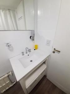 Un baño blanco con lavabo y espejo. en Center 208 - DAT (Habilitación 170/2018), en San Carlos de Bariloche