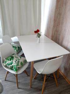una mesa blanca con dos sillas y una flor roja en un jarrón en Center 208 - DAT (Habilitación 170/2018), en San Carlos de Bariloche