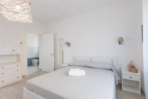 a white bedroom with a white bed and a bathroom at Vento e Mare in Riotorto