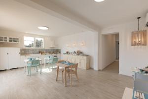 eine Küche mit weißen Schränken sowie Tischen und Stühlen in der Unterkunft Vento e Mare in Riotorto