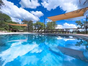 a swimming pool with a blue sky and clouds at Ongava Lodge in Okaukuejo