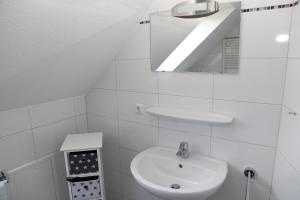 ein weißes Badezimmer mit Waschbecken und Spiegel in der Unterkunft Kyana in Norden + 9 Fotos