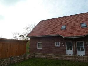 ein rotes Backsteinhaus mit einem Holzzaun in der Unterkunft Kyana in Norden