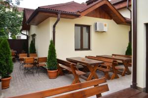 eine Terrasse mit Holzbänken, Tischen und Stühlen in der Unterkunft Casa Transilvania in Satu Mare