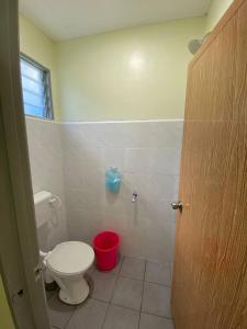 a bathroom with a toilet and a red bucket at Room/Homestay NazaDja in Sungai Besar