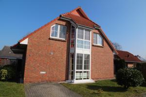 a red brick house with a large window at Robbeninsel in Norden
