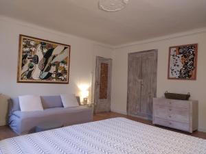 een slaapkamer met een wit bed en een bank bij Agriturismo Podere Luciano in Acqui Terme