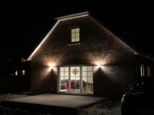 a brick house with a window at night at Stüürmanns Huus in Hilgenriedersiel
