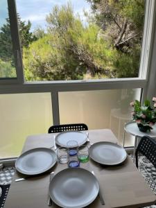 una mesa con platos y utensilios y una ventana en Appartement familial à 50m de la plage - Narbonne Plage - 4LBM492, en Mosset