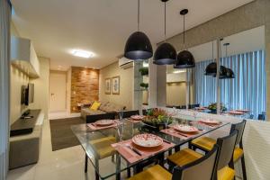 a dining room and living room with a table and chairs at Varandas do Atlântico, Condo Frente Mar com Piscina Climatizada - 3 quartos 6 pessoas in Bombinhas