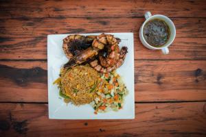 un plato de comida con camarones y arroz y una taza de café en Hotel Sunshine Enugu, en Enugu