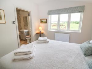 a bedroom with a white bed with towels on it at Flagstone Cottage in Cheltenham