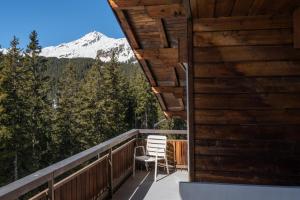 a balcony with a chair and a snow covered mountain at Casa Dschember, Wohnung 11, 1-6 Personen in Arosa