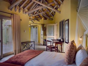 a bedroom with a bed and a table and a desk at Ongava Lodge in Okaukuejo