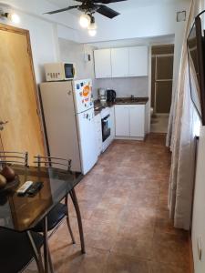 a kitchen with a table and a white refrigerator at fucsia in Rosario +3 photos