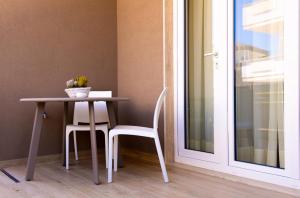 une table et deux chaises à côté d'une fenêtre dans l'établissement Domina Apartments, à Monopoli