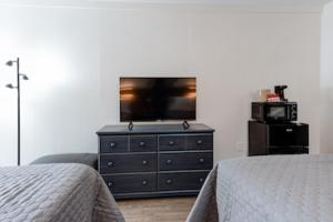 - une chambre avec deux lits et une commode avec une télévision dans l'établissement Heart of the Valley Motel, à Maggie Valley