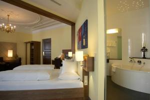 a bedroom with a bed and a tub and a sink at Hotel Weißes Kreuz in Bregenz
