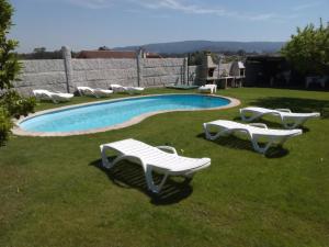 una piscina con bancos blancos en el césped en Casa Laura Sanxenxo, en Sanxenxo
