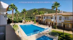 a swimming pool in front of a house with palm trees at Casa Rural las Rosas de Benaojan in Benaoján