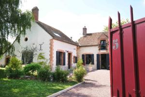 una casa con un cancello rosso in un cortile di L'Orme Blanchet Spa & Piscine, petit-déjeuner inclus a Chambon-la-Forêt