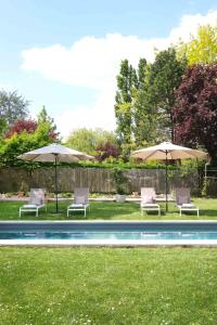 a group of chairs and umbrellas next to a pool at L'Orme Blanchet Spa & Piscine, petit-déjeuner inclus in Chambon-la-Forêt