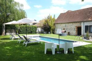 a backyard with a pool with chairs and an umbrella at L'Orme Blanchet Spa & Piscine, petit-déjeuner inclus in Chambon-la-Forêt