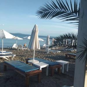 a beach with chairs and umbrellas and the ocean at Studio in the center of Sarafovo in Burgas City