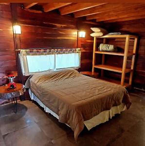 sypialnia z łóżkiem i drewnianą ścianą w obiekcie La Azotea cabañas & suites w mieście La Cumbrecita