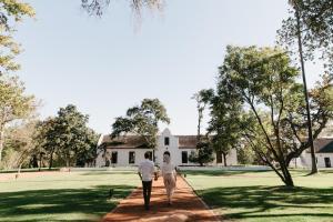 een man en vrouw die op een pad lopen naar een wit huis bij Spier Hotel and Wine Farm in Stellenbosch