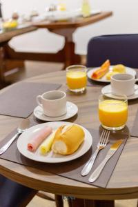 una mesa con un plato de alimentos para el desayuno y zumo de naranja en Pousada Água Eterna - Próximo ao Museu de Cera, Hot Beach e Thermas dos Laranjais - By UP Hotel, en Olímpia