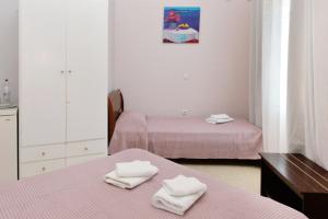 two beds in a room with pink sheets and towels at Hotel Villa Plaza in Spetses