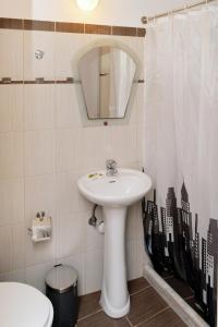 ein Badezimmer mit einem Waschbecken, einem Spiegel und einem WC in der Unterkunft Hotel Villa Plaza in Spetses