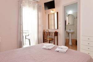a bedroom with a bed with two towels on it at Hotel Villa Plaza in Spetses +7 photos