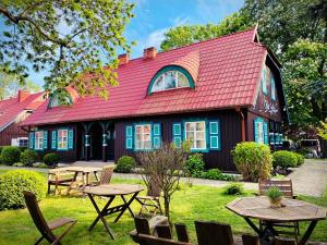 a red roofed building with picnic tables in front of it at Vila Jelita in Nida