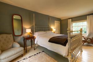 een slaapkamer met een bed, een stoel en een spiegel bij Haclins Cottage - Norfolk Holiday Properties in Fakenham