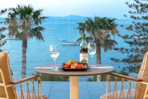 a table with a plate of fruit and two glasses of wine at KoSea Boutique Hotel in Kos