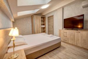 a bedroom with a large bed and a flat screen tv at Complex Hunter's Beach in Shkorpilovtsi