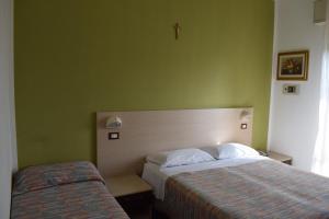 1 dormitorio con 2 camas y una cruz en la pared en Hotel Gattuccio, en Cesenatico