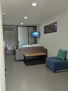 Habitación con cama, sofá y TV. en Berilo Deluxe Apartahotel, en Barranquilla