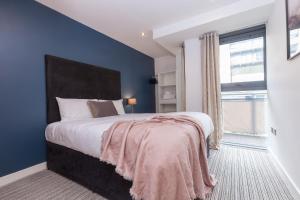 a bedroom with a large bed with a blue wall at KSpace @ West One in Sheffield