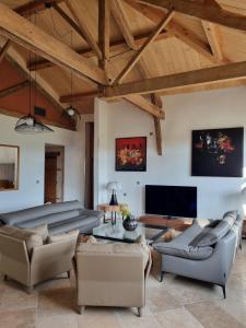 a living room with couches and a flat screen tv at Les Collines du Quercy Blanc in Castelnau-de-Montratier